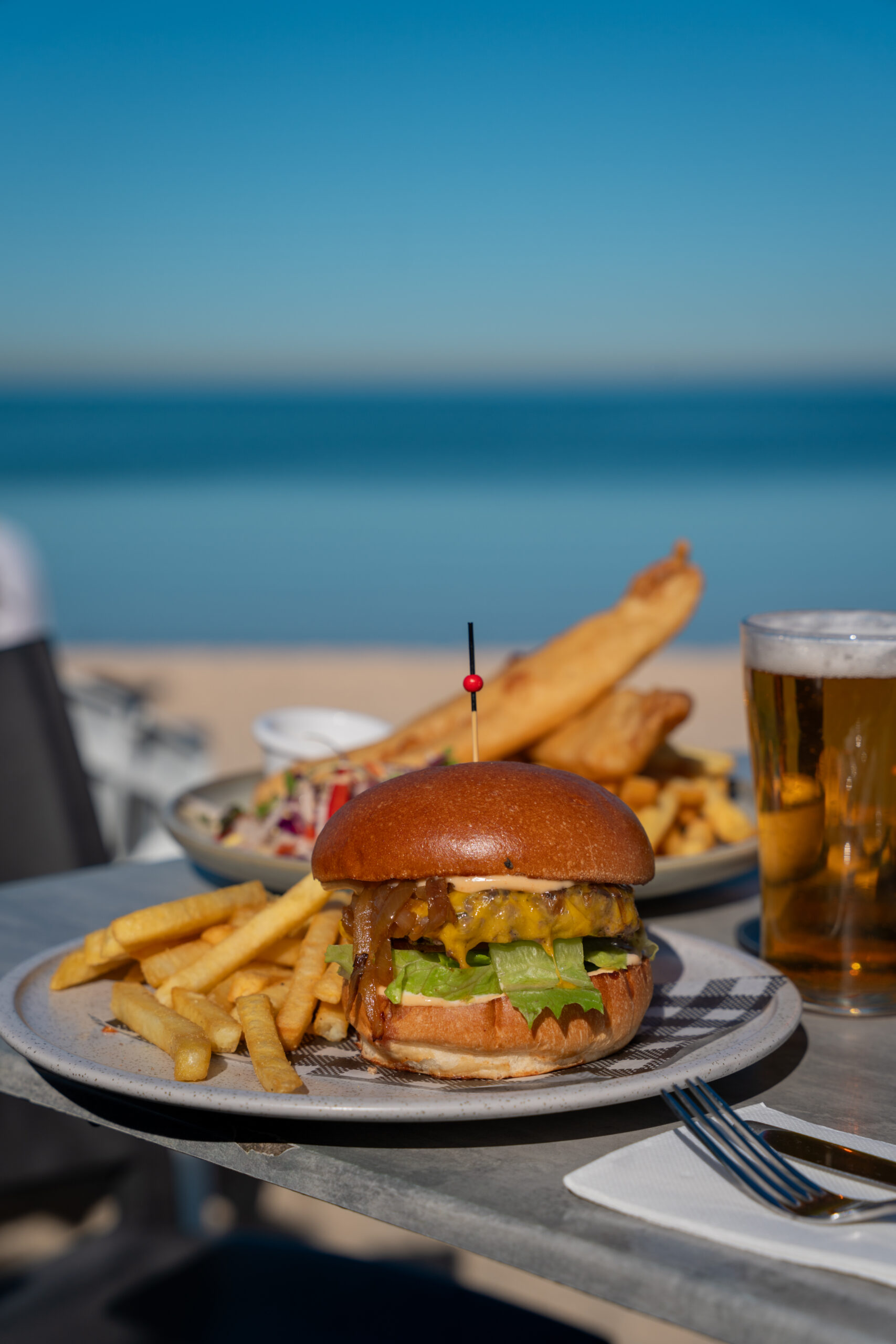 Classic cheeseburger with beef pattie, American cheddar, lettuce, tomato, caramelised onion, and burger sauce in a milk bun, served with chips.