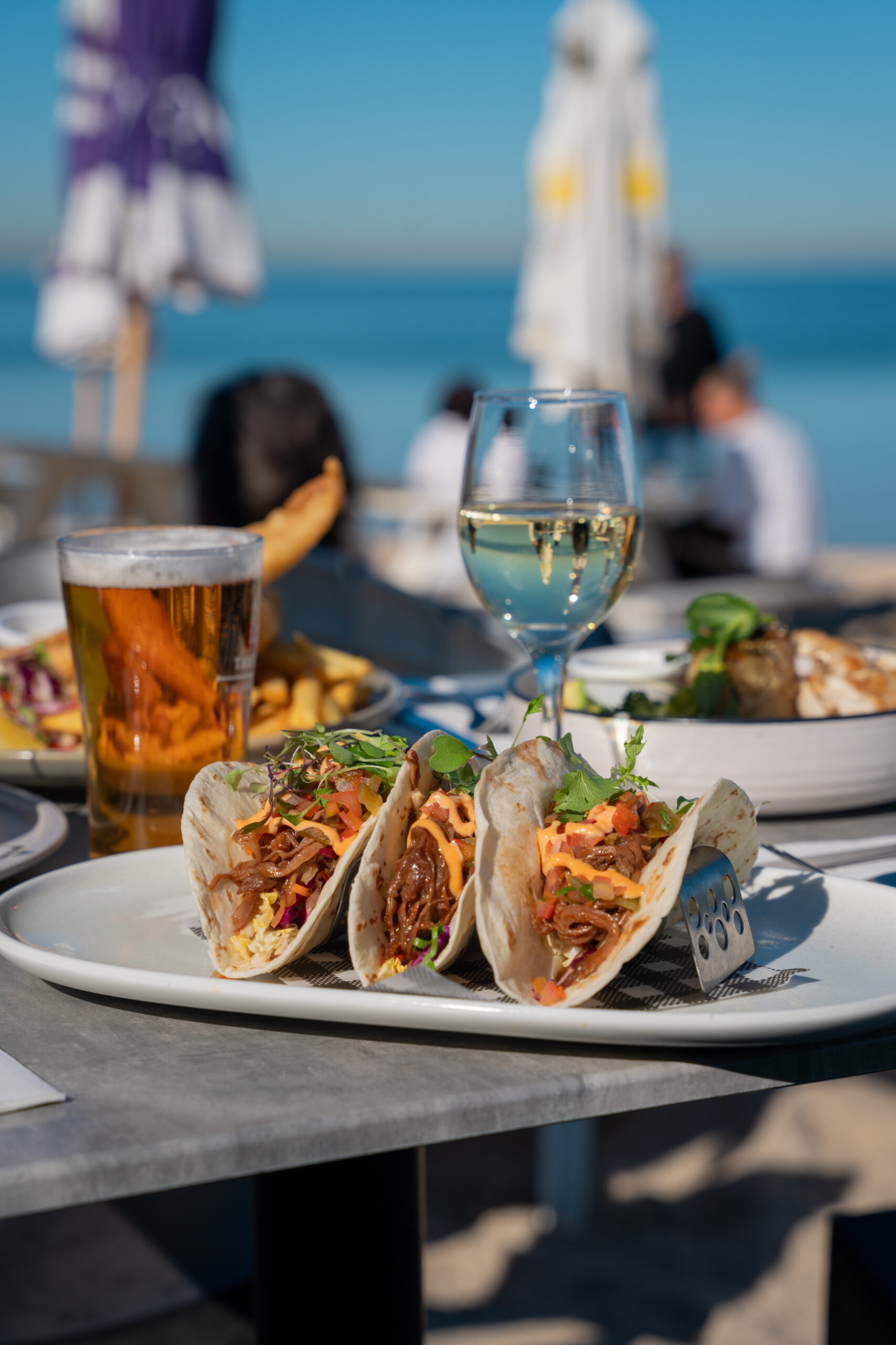 Three BBQ brisket tacos in soft flour tortillas with cabbage slaw, tomato, coriander, jalapeño salsa, and chipotle mayo